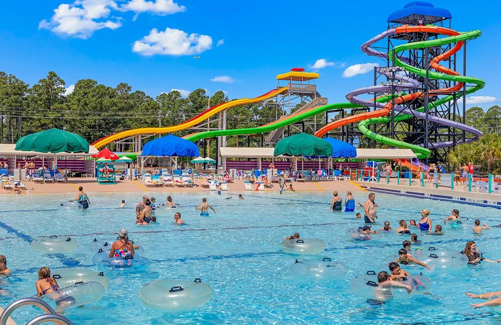 A large swimming pool with a water slide and people in the water.
