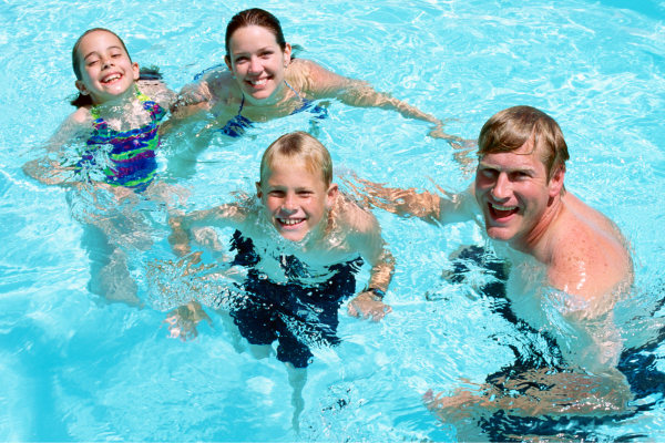 Smiling family of four in a swimming pool