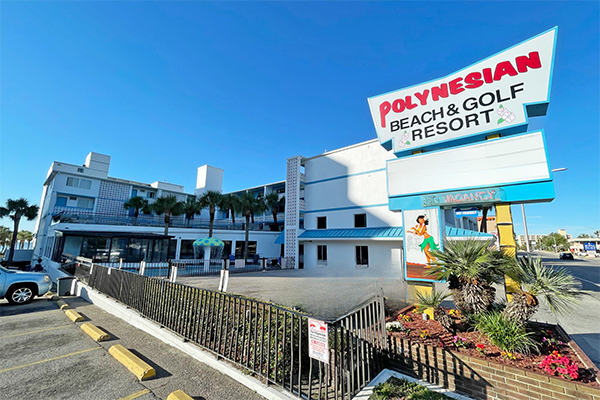 Exterior view of a hotel with a sign that says Polynesian Beach and Golf Resort