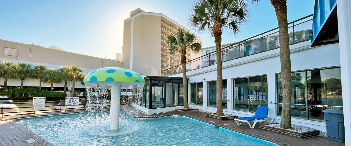 Exterior view of a hotel pool with an umbrella style water feature